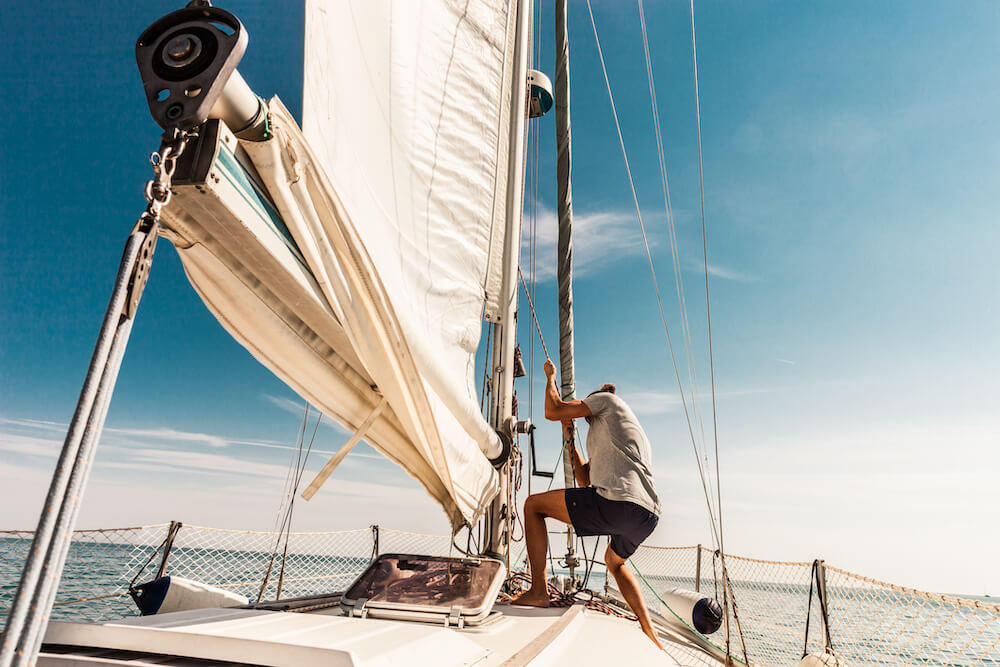 A person prepares the sail on a sailing boat. 