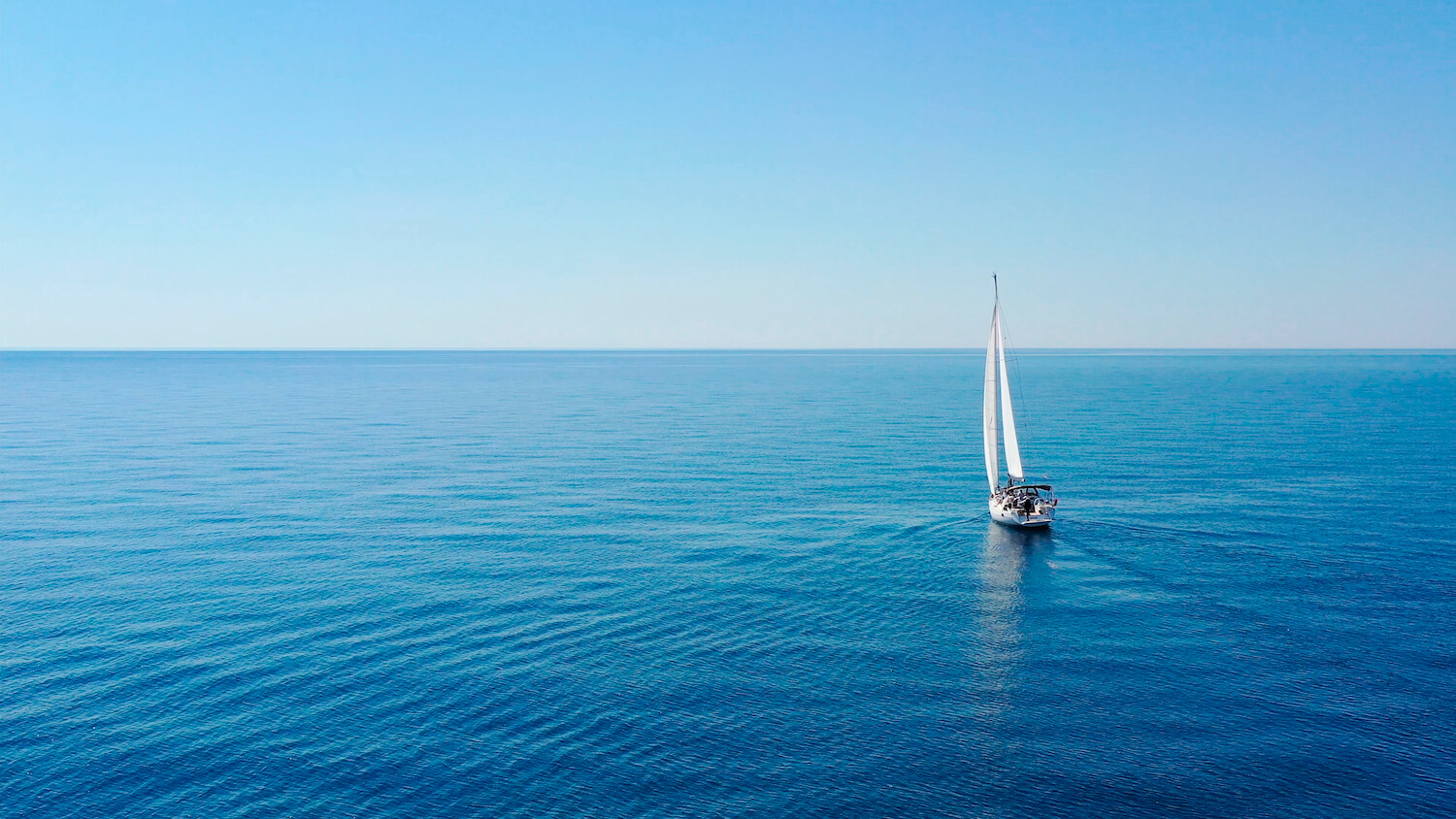 A calm sea with a sailing ship on it. 