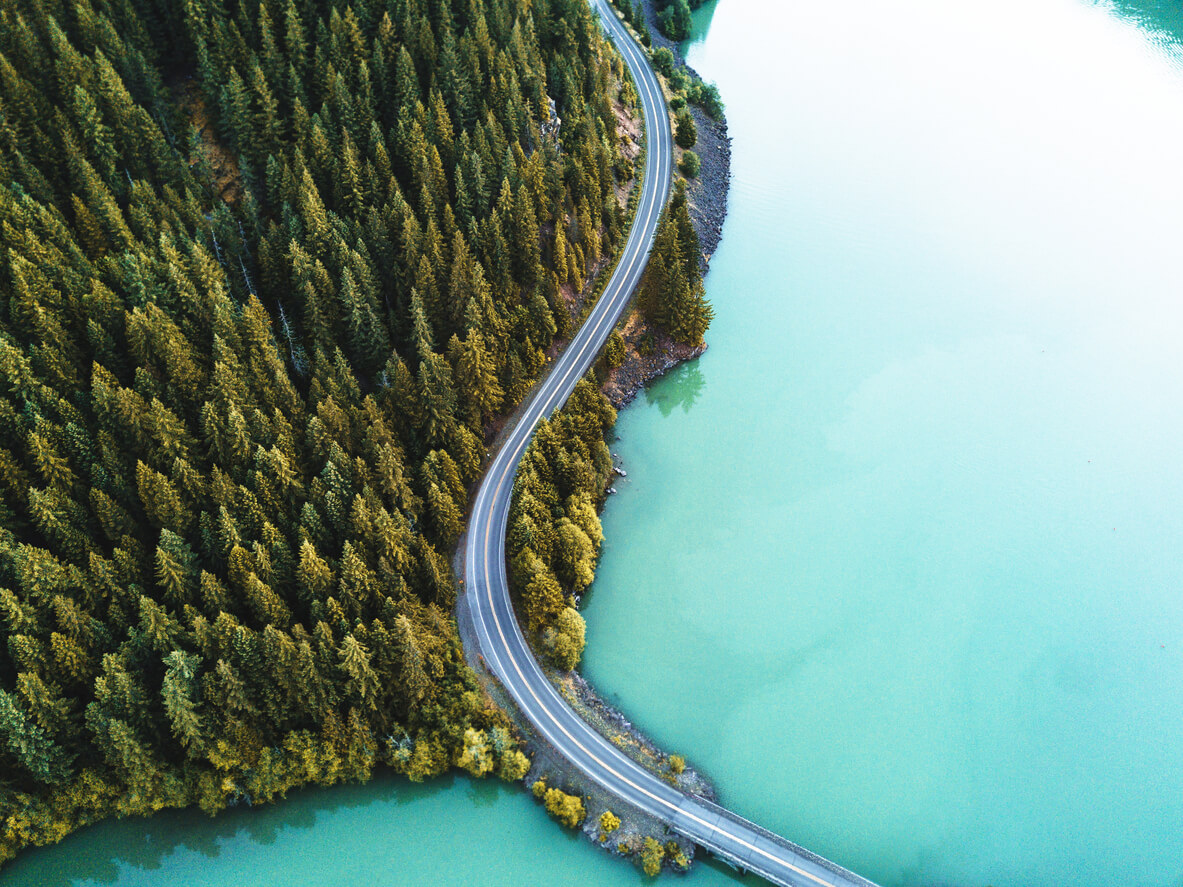 A road connecting a forrest peninsula amidst a big greenish-blue lake