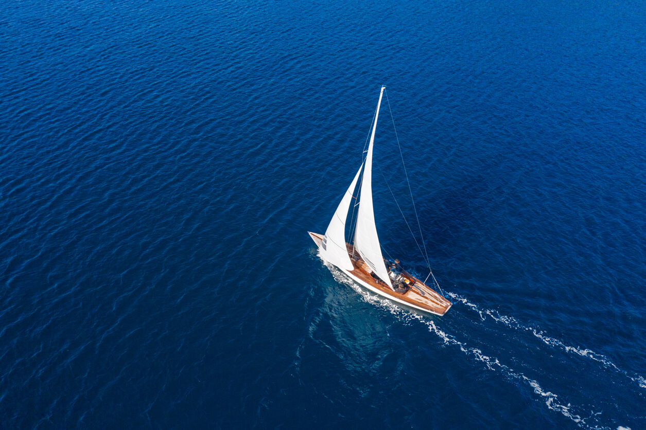 Ein Segelboot fährt über ein dunkelblaues Meer