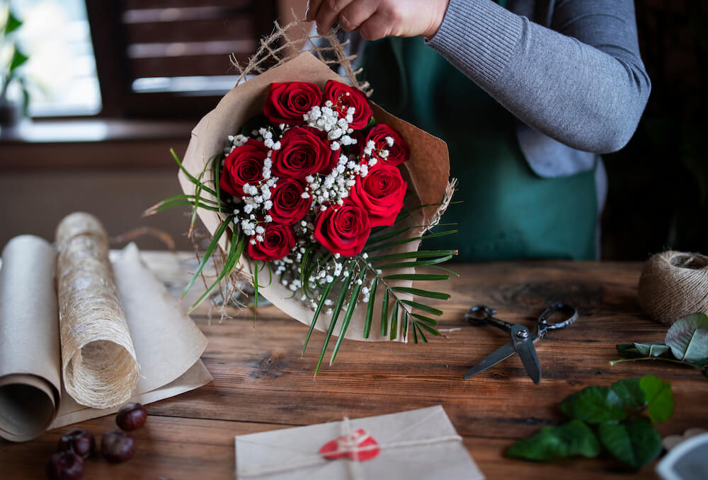 Eine Person stellt einen schönen Rosenblumenstrauß zusammen. 