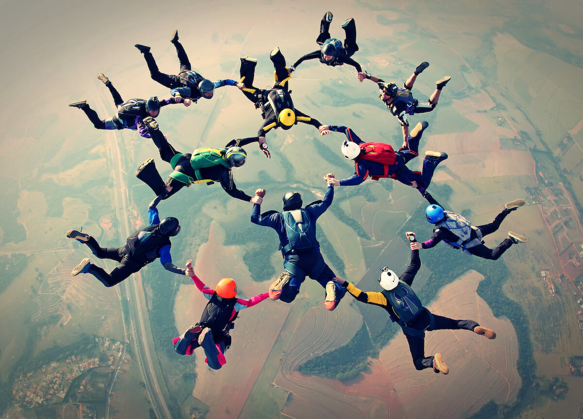 A big group of paragliders holding hands. 