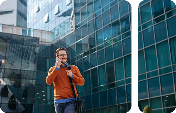 Modern dressed man under skyscrapers talking on smartphone and laughing