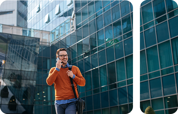 Modern gekleideter Mann unter Wolkenkratzern, der mit seinem Smartphone telefoniert und lacht