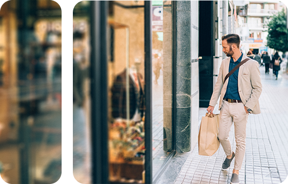 A man stands in front of a modern building and looks into the shop window