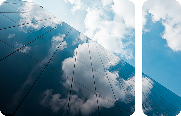 Ein Wolkenkratzer mit Glasfront, in der sich Wolken spiegeln. 