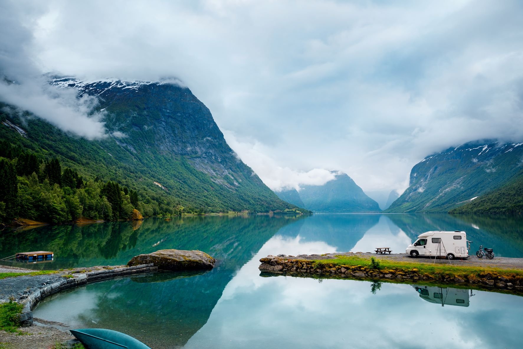 A blue mountain lake with a camper at the shore. 