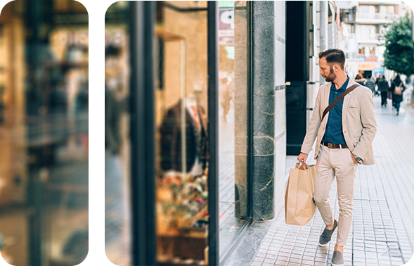 A man stands in front of a modern building and looks into the shop window