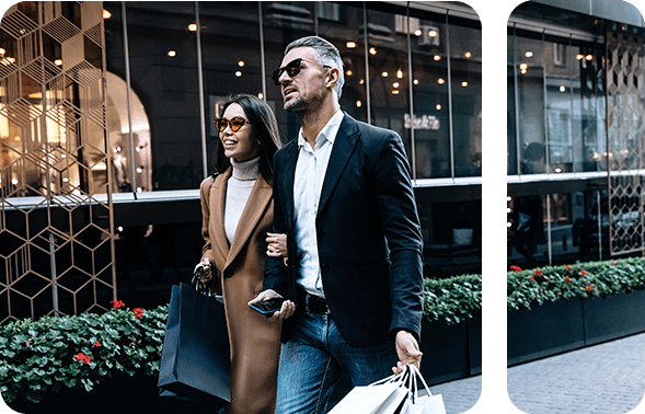 A woman and a man walking through a city carrying shopping bags
